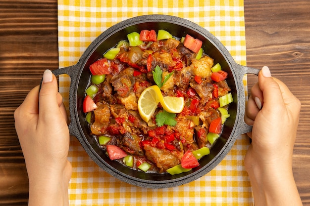 Vista superior da refeição de vegetais cozidos com carne e pimentões fatiados na mesa de madeira marrom