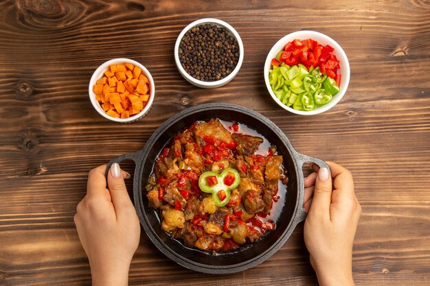 Vista superior da refeição de vegetais cozidos com temperos e pimenta fatiada na mesa de madeira marrom