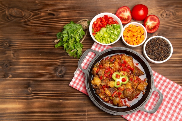 Vista superior da refeição de vegetais cozidos, incluindo molho de vegetais e carne na mesa marrom