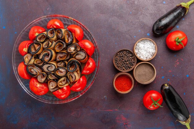 Vista superior da refeição de vegetais fatiados e laminados de tomates com berinjelas e temperos no fundo escuro