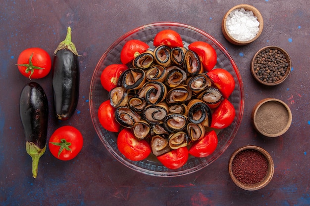 Vista superior da refeição de vegetais fatiados e laminados de tomates com berinjelas e temperos no fundo escuro