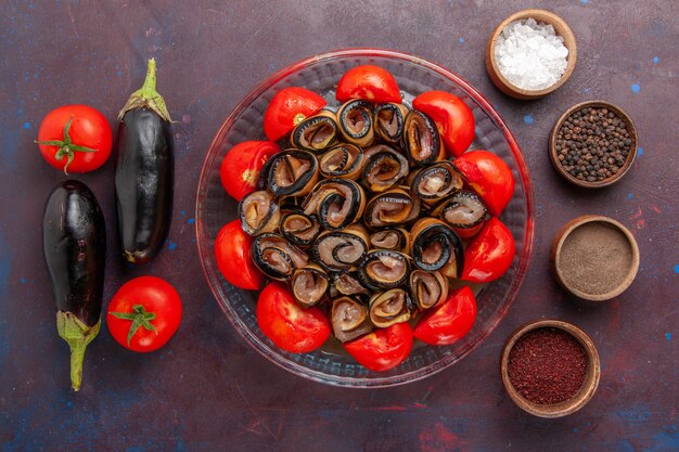 Vista superior da refeição de vegetais fatiados e laminados de tomates com berinjelas e temperos no fundo escuro