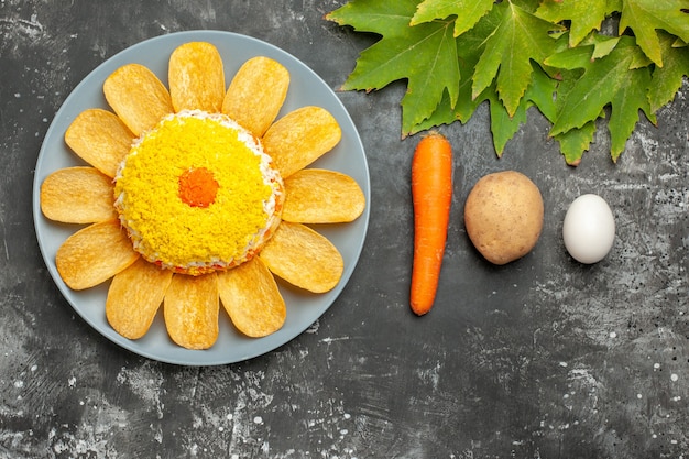 Vista superior da salada com cenoura, batata e ovo e folhas em fundo escuro