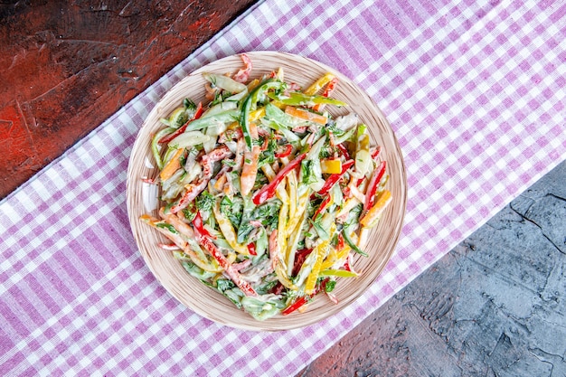 Vista superior da salada de vegetais no prato na toalha de mesa na mesa vermelha escura