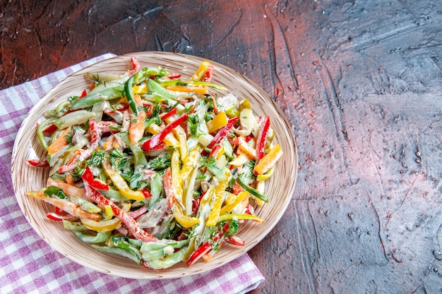 Foto grátis vista superior da salada de vegetais no prato na toalha de mesa no espaço livre da mesa vermelha escura