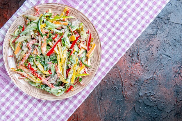 Vista superior da salada de vegetais no prato na toalha de mesa no lugar de cópia da mesa vermelho escuro