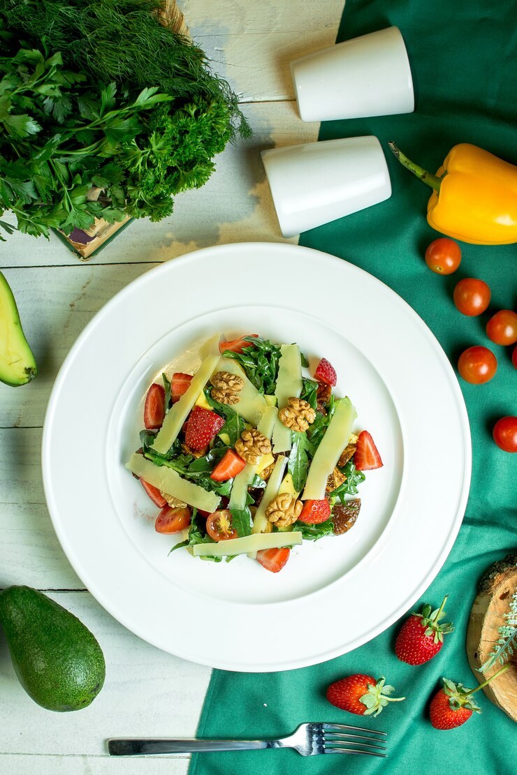 Foto grátis vista superior da salada fresca com queijo parmesão nozes tomate cereja e morangos em uma tigela branca