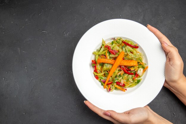 Vista superior da salada uma salada apetitosa com legumes no prato nas mãos