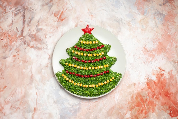 Vista superior da salada verde em formato de árvore de ano novo dentro do prato com luz de fundo