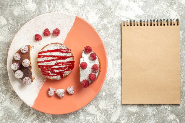 Vista superior da sobremesa doce com molho e frutas vermelhas com bloco de notas ao lado no fundo de mármore