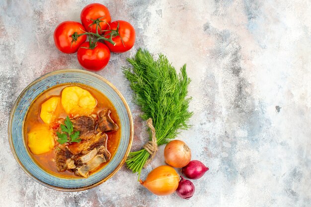 Vista superior da sopa bozbash caseira um punhado de tomates e cebolas de endro na superfície nua