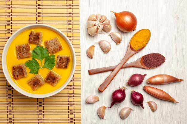 Foto grátis vista superior da sopa de abóbora com bolachas de pão e alho no branco