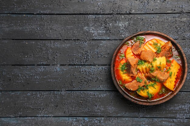 Vista superior da sopa de carne com batatas e verduras no chão escuro