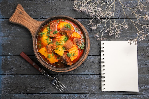 Vista superior da sopa de molho de carne com verduras e batatas na mesa escura