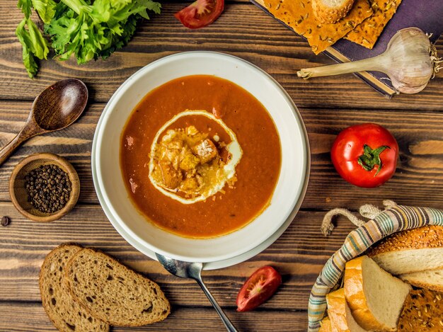 Vista superior da sopa de tomate com queijo derretido e bolacha nele