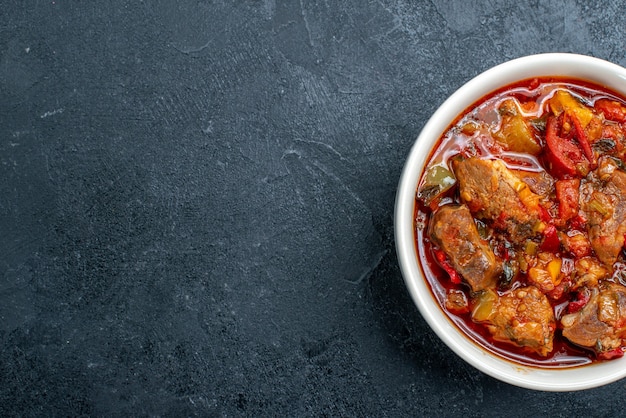 Vista superior da sopa de vegetais com carne dentro do prato em cinza escuro