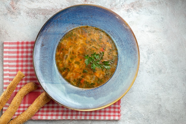 Vista superior da sopa quente de vegetais com verduras dentro do prato no espaço em branco