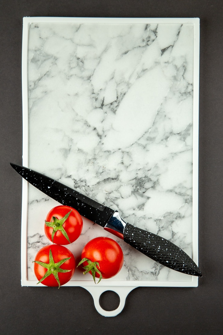 Foto grátis vista superior da tábua de corte branca com tomates vermelhos na superfície escura