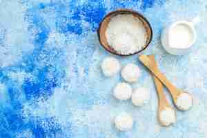 Foto grátis vista superior da tigela de pó de coco e bolas de coco em fundo branco azul