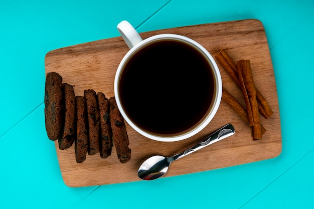 Foto grátis vista superior da xícara de café e biscoitos com colher na tábua sobre fundo azul