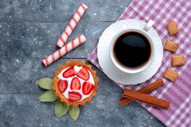 Vista superior da xícara de café quente e forte junto com bolo e canela na mesa cinza, doce de café, bebida doce, biscoito de cacau