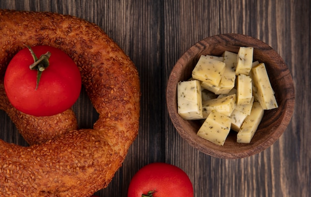 Foto grátis vista superior das fatias de queijo em uma tigela de madeira com tomates em um fundo de madeira