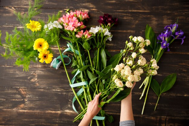 Vista superior das flores, florista em processo de fazer buquê