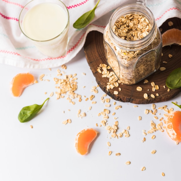 Foto grátis vista superior das folhas de manjericão; fatias de laranja; aveia; leite e guardanapo sobre fundo branco