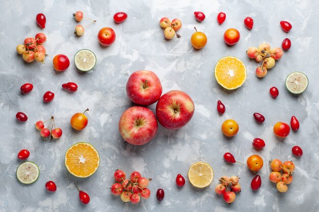 Vista superior das maçãs vermelhas com limão e cerejas na mesa branca