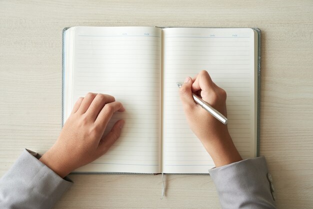 Vista superior das mãos da pessoa irreconhecível pronta para preencher o planejador