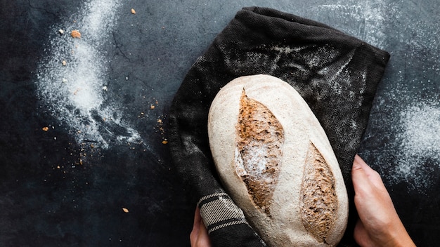 Vista superior das mãos segurando um pão no pano