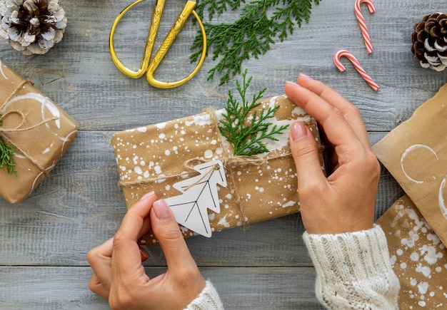 Vista superior das mãos segurando um presente de Natal embrulhado com bastões de doces