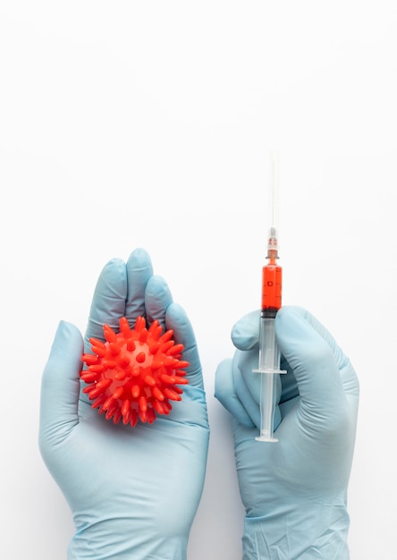Foto grátis vista superior das mãos segurando uma seringa e vírus