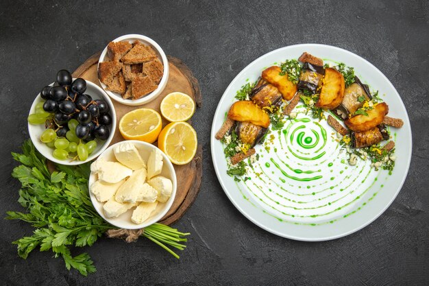 Vista superior das uvas frescas com queijo branco, verdes e limão na superfície escura, refeição com leite, frutas