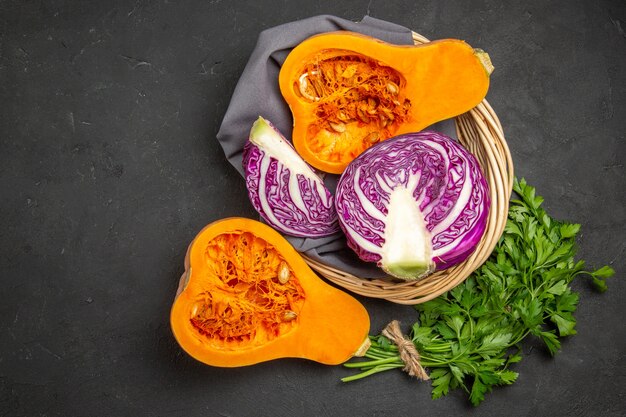 Vista superior de abóbora fresca com verduras e repolho roxo em fundo escuro