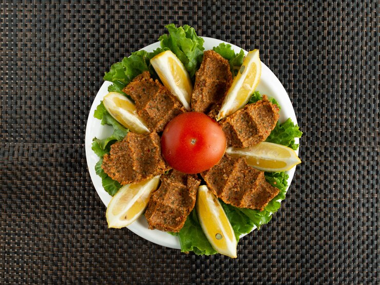 Foto grátis vista superior de almôndegas cruas de cof kofte turco servidas com alface e limão