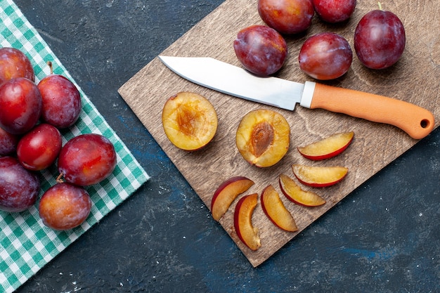 Vista superior de ameixas frescas inteiras maduras e suculentas em uma mesa cinza-escuro, frutas com vitaminas frescas no verão