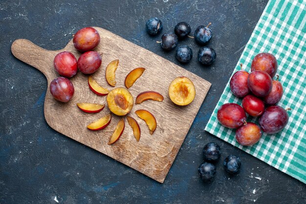 Vista superior de ameixas frescas inteiras maduras e suculentas fatiadas no verão escuro de vitamina