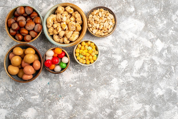 Foto grátis vista superior de avelãs e amendoins com doces na superfície branca