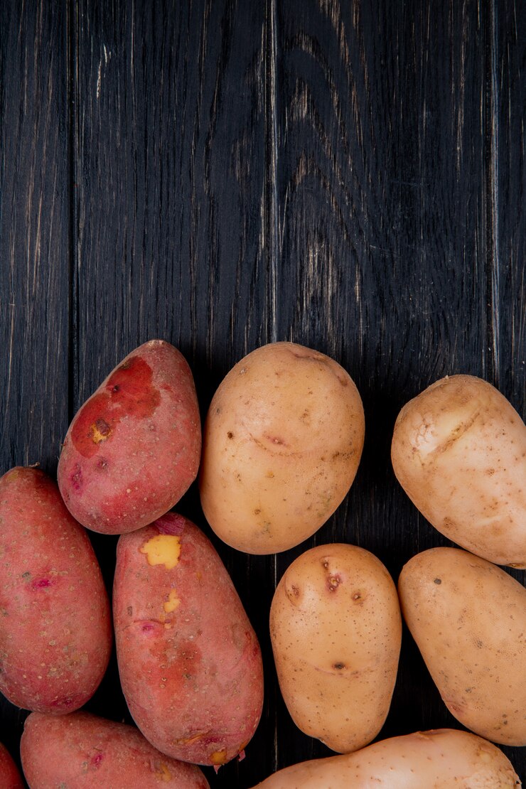 Foto grátis vista superior de batatas brancas e vermelhas na superfície de madeira com espaço de cópia