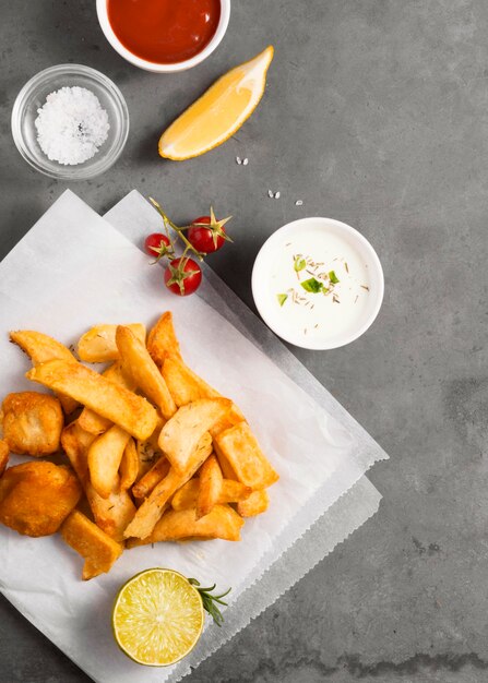 Vista superior de batatas fritas com tigela de molho e ketchup