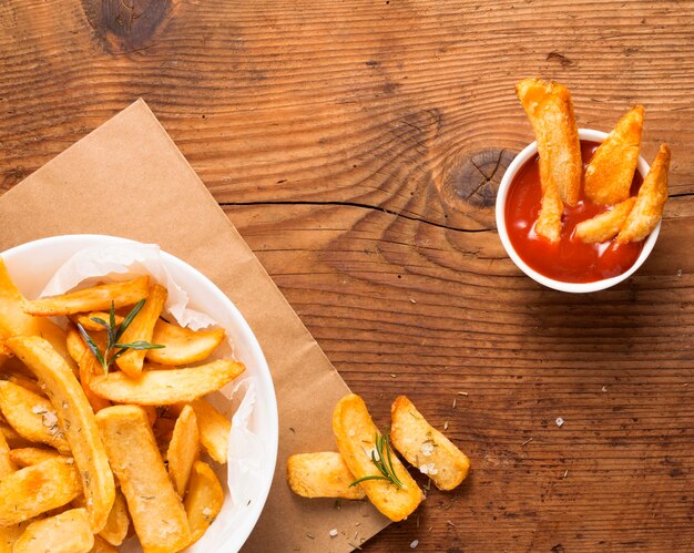 Vista superior de batatas fritas no prato com tigela de ketchup