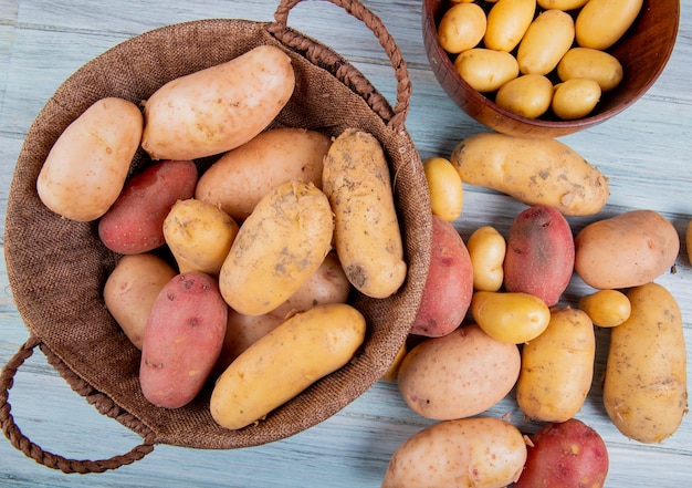 Foto grátis vista superior de batatas na cesta com novas na tigela e outros de diferentes tipos na superfície de madeira