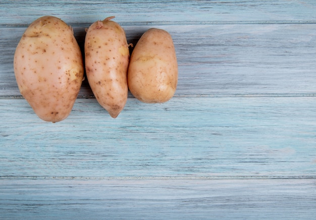 Foto grátis vista superior de batatas russet no lado esquerdo e superfície de madeira com espaço de cópia