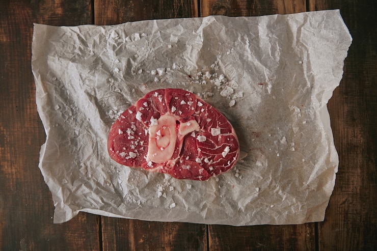 Foto grátis vista superior de bife de carne crua salgada em papel artesanal em mesa de madeira grossa escovada de grunge