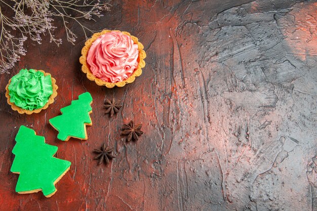 Foto grátis vista superior de biscoitos de árvore de natal de diferentes tamanhos, tortas de anis na superfície vermelha escura