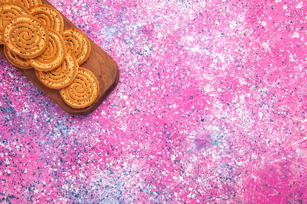 Vista superior de biscoitos doces redondos alinhados na superfície rosa