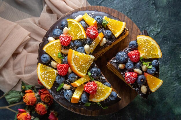 Vista superior de bolo de chocolate gostoso com frutas no escuro