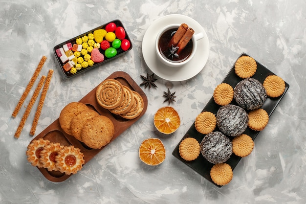 Foto grátis vista superior de bolos de chocolate com biscoitos doces e xícara de chá na superfície branca