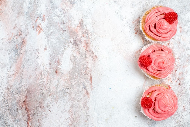 Vista superior de bolos de morango rosa com creme na superfície branca